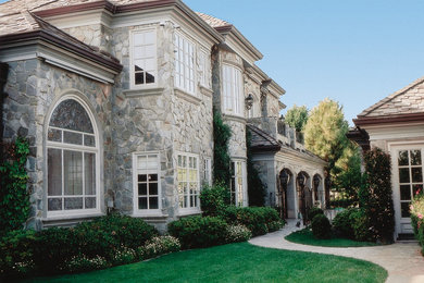 Example of a large tuscan gray two-story stone gable roof design in Kansas City