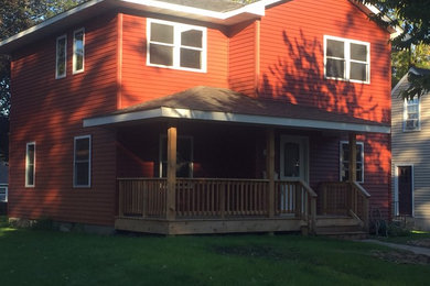 Photo of a mid-sized traditional two-storey red exterior in Minneapolis with vinyl siding and a hip roof.