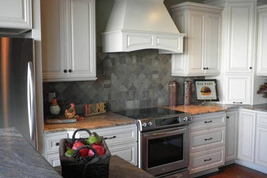 Large trendy l-shaped ceramic tile eat-in kitchen photo in Chicago with a drop-in sink, recessed-panel cabinets, white cabinets, granite countertops, gray backsplash, stone tile backsplash, stainless steel appliances and an island
