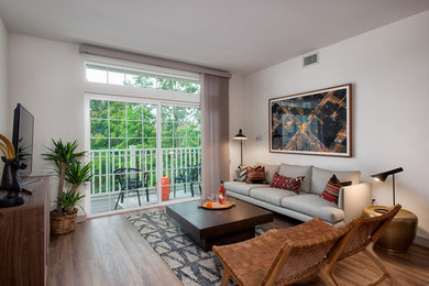 Inspiration for a mid-sized contemporary enclosed medium tone wood floor and brown floor family room remodel in New York with white walls, no fireplace and a tv stand