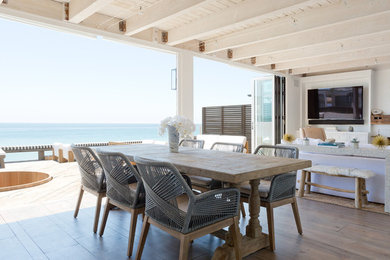 Kitchen/dining room combo - mid-sized coastal medium tone wood floor, brown floor and exposed beam kitchen/dining room combo idea in Los Angeles with a standard fireplace, white walls and a brick fireplace