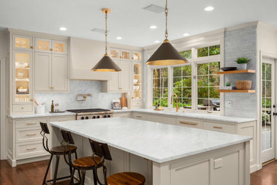 Large transitional u-shaped medium tone wood floor and brown floor kitchen photo in Seattle with an undermount sink, recessed-panel cabinets, marble countertops, white backsplash, marble backsplash, paneled appliances, an island and white countertops