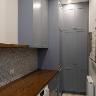 Esempio di una grande sala lavanderia mediterranea con lavello da incasso, ante in stile shaker, ante grigie, top in legno, pareti multicolore, pavimento in cemento, lavatrice e asciugatrice affiancate e pavimento giallo