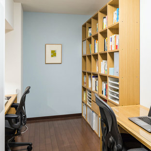 Mittelgroßes Nordisches Arbeitszimmer ohne Kamin mit Arbeitsplatz, blauer Wandfarbe, dunklem Holzboden, freistehendem Schreibtisch, Tapetendecke und Tapetenwänden in Tokio