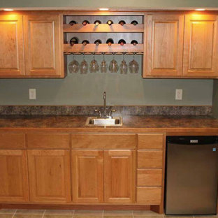 ミネアポリスの小さいトラディショナルスタイルのおしゃれなウェットバー (アンダーカウンターシンク、レイズドパネル扉のキャビネット、淡色木目調キャビネット、ラミネートカウンター、緑のキッチンパネル、ラミネートの床、茶色い床、マルチカラーのキッチンカウンター) の写真