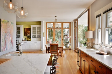 Eat-in kitchen - mid-sized transitional l-shaped medium tone wood floor and brown floor eat-in kitchen idea in Austin with medium tone wood cabinets, marble countertops, an island, a farmhouse sink, shaker cabinets, gray backsplash, stone tile backsplash, stainless steel appliances and white countertops