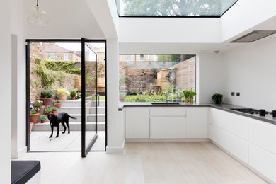 Photo of a kitchen in London with white cabinets and black worktops.