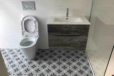 ロンドンにある小さなトラディショナルスタイルのおしゃれなバスルーム (浴槽なし) (濃色木目調キャビネット、バリアフリー、白いタイル、セラミックタイル、セラミックタイルの床、壁付け型シンク、マルチカラーの床、開き戸のシャワー) の写真