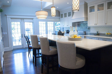 Inspiration for a mid-sized transitional galley medium tone wood floor kitchen remodel in Calgary with an undermount sink, shaker cabinets, white cabinets, multicolored backsplash, ceramic backsplash, stainless steel appliances and an island
