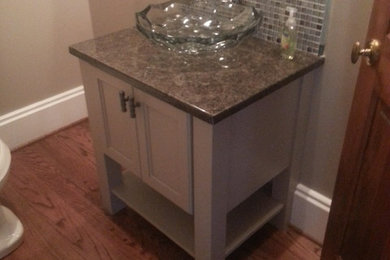 Inspiration for a small transitional 3/4 beige tile and stone tile light wood floor bathroom remodel in Charlotte with a vessel sink, recessed-panel cabinets, beige cabinets, granite countertops, a two-piece toilet and beige walls
