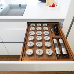 Mid-sized contemporary kitchen pantry pictures - Example of a mid-sized trendy single-wall painted wood floor and brown floor kitchen pantry design in Cologne with white cabinets, an integrated sink, white backsplash and an island