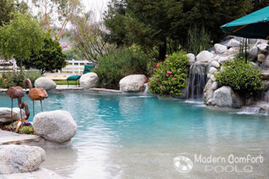 Design ideas for a medium sized traditional back custom shaped natural swimming pool in New York with a water feature.
