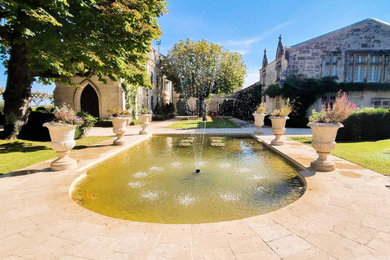 Cette image montre un grand jardin à la française traditionnel avec un bassin, une exposition ensoleillée et des pavés en pierre naturelle.