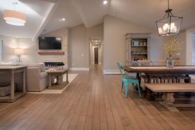 Example of a large arts and crafts open concept light wood floor and brown floor living room design in Denver with beige walls, a hanging fireplace, a brick fireplace and a wall-mounted tv