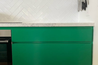 This is an example of a mid-sized contemporary galley eat-in kitchen in Sydney with a double-bowl sink, recessed-panel cabinets, green cabinets, marble benchtops, white splashback, ceramic splashback, with island and white benchtop.