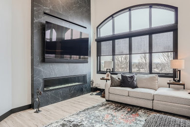 На фото: большая парадная, открытая гостиная комната в стиле модернизм с серыми стенами, полом из ламината, горизонтальным камином, фасадом камина из плитки, телевизором на стене и бежевым полом