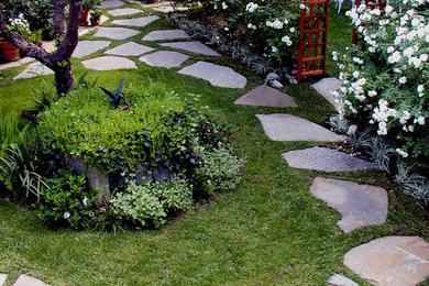 Photo of a large traditional backyard partial sun formal garden for spring in Los Angeles with natural stone pavers and a garden path.