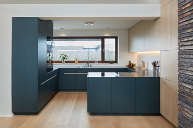 Offene, Geräumige Moderne Küche mit flächenbündigen Schrankfronten, hellem Holzboden und Halbinsel in Köln