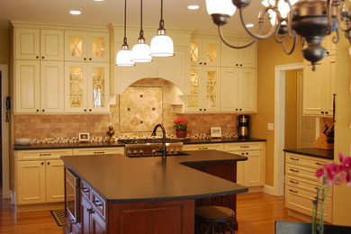 Enclosed kitchen - large traditional u-shaped light wood floor enclosed kitchen idea in Boston with a farmhouse sink, recessed-panel cabinets, white cabinets, granite countertops, subway tile backsplash, paneled appliances and an island