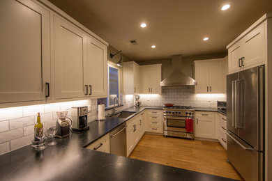 This is an example of a mid-sized contemporary u-shaped separate kitchen in Sacramento with an undermount sink, shaker cabinets, white cabinets, soapstone benchtops, white splashback, subway tile splashback, stainless steel appliances, light hardwood floors, no island and brown floor.