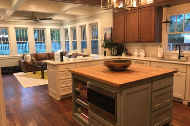 Inspiration for a mid-sized arts and crafts u-shaped open plan kitchen in Dallas with a farmhouse sink, glass-front cabinets, medium wood cabinets, quartzite benchtops, white splashback, ceramic splashback, panelled appliances, medium hardwood floors, with island, brown floor and white benchtop.