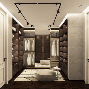 Modelo de armario vestidor de mujer, minimalista, grande, con armarios abiertos, suelo marrón, puertas de armario de madera en tonos medios y suelo de madera oscura