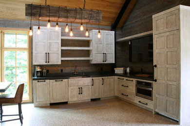 Open concept kitchen - huge rustic l-shaped concrete floor and brown floor open concept kitchen idea in Grand Rapids with a farmhouse sink, beaded inset cabinets, light wood cabinets, concrete countertops, brown backsplash, wood backsplash, paneled appliances, no island and black countertops