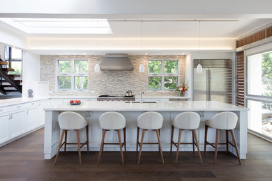 Enclosed kitchen - large tropical l-shaped dark wood floor and brown floor enclosed kitchen idea in Hawaii with an undermount sink, shaker cabinets, white cabinets, solid surface countertops, multicolored backsplash, matchstick tile backsplash, stainless steel appliances, an island and white countertops