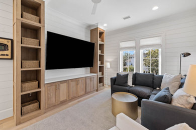 Example of a large beach style loft-style light wood floor and shiplap wall family room library design in Other with white walls and a wall-mounted tv
