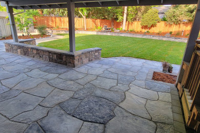 Diseño de jardín grande en patio trasero con adoquines de piedra natural