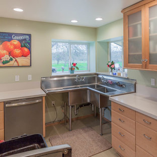 Cette image montre une arrière-cuisine parallèle urbaine de taille moyenne avec un évier 3 bacs, un placard avec porte à panneau encastré, des portes de placard en bois brun, un plan de travail en inox, une crédence blanche, un électroménager en acier inoxydable, un sol en vinyl et aucun îlot.