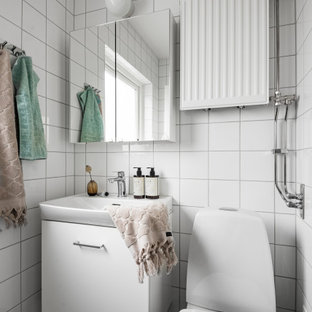 Inspiration för minimalistiska badrum, med släta luckor, vita skåp, en toalettstol med separat cisternkåpa, vit kakel, ett konsol handfat och svart golv