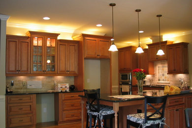 Example of a mid-sized trendy l-shaped medium tone wood floor eat-in kitchen design in Detroit with raised-panel cabinets, medium tone wood cabinets, granite countertops, beige backsplash, stainless steel appliances, an island and stone tile backsplash