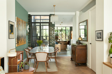 Large contemporary open plan dining in London with green walls and medium hardwood floors.
