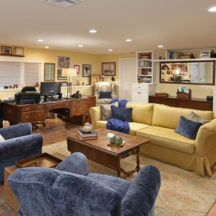 Exempel på ett stort klassiskt arbetsrum, med gula väggar, klinkergolv i terrakotta, ett fristående skrivbord, brunt golv och ett bibliotek