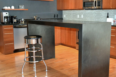 Inspiration for a mid-sized industrial l-shaped light wood floor eat-in kitchen remodel in Denver with medium tone wood cabinets, blue backsplash, stainless steel appliances, an island, flat-panel cabinets and ceramic backsplash