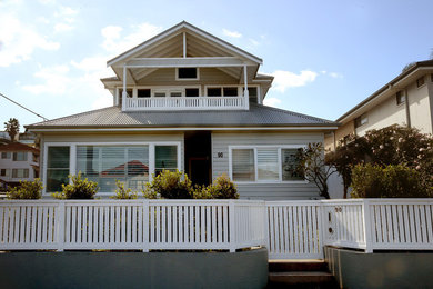 Large beach style two-storey beige house exterior in Sydney with wood siding, a gable roof and a metal roof.