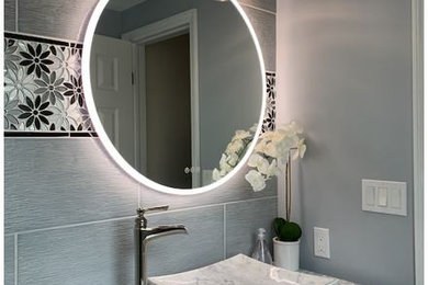 Inspiration for a mid-sized eclectic gray tile and porcelain tile marble floor and white floor powder room remodel in New York with shaker cabinets, white cabinets, a one-piece toilet, gray walls, a vessel sink, marble countertops, white countertops and a freestanding vanity