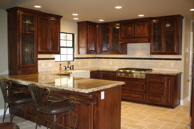 Eat-in kitchen - u-shaped eat-in kitchen idea in Other with a farmhouse sink, raised-panel cabinets, dark wood cabinets, granite countertops, beige backsplash, stone tile backsplash and stainless steel appliances