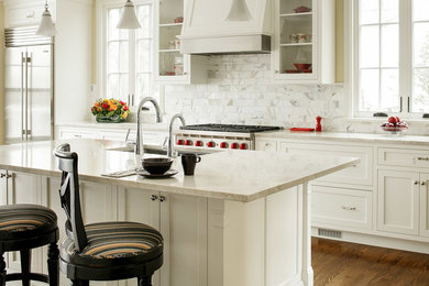 Inspiration for a large timeless l-shaped medium tone wood floor eat-in kitchen remodel in New York with an undermount sink, recessed-panel cabinets, white cabinets, marble countertops, gray backsplash, subway tile backsplash, stainless steel appliances and an island