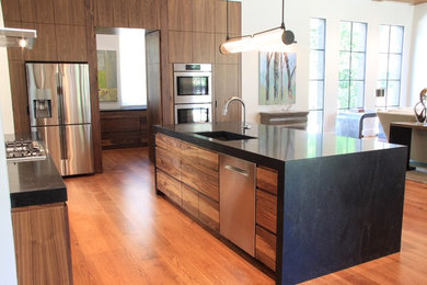 Eat-in kitchen - mid-sized contemporary l-shaped medium tone wood floor eat-in kitchen idea in Atlanta with stainless steel appliances, an island, black countertops, black backsplash, stone slab backsplash and granite countertops