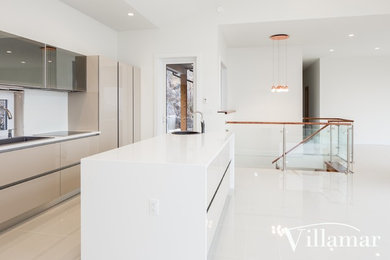 Large modern l-shaped open plan kitchen in Vancouver with a drop-in sink, flat-panel cabinets, beige cabinets, quartz benchtops, white splashback, window splashback, stainless steel appliances, porcelain floors and with island.
