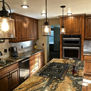 Exempel på ett stort kök, med en undermonterad diskho, luckor med upphöjd panel, granitbänkskiva, stänkskydd i travertin, svarta vitvaror, ljust trägolv och en köksö