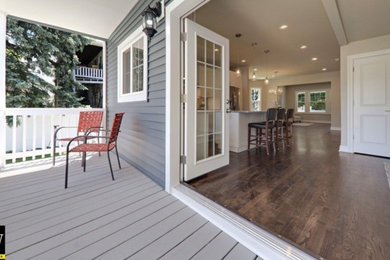 This is an example of a large wood railing front porch design in Chicago with decking and an awning.