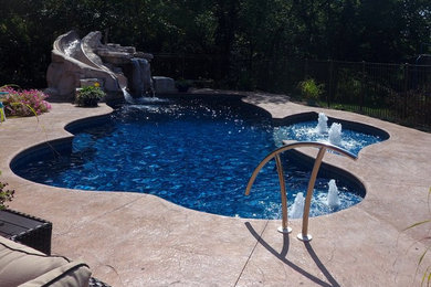 Ejemplo de piscina con tobogán tradicional de tamaño medio a medida en patio trasero