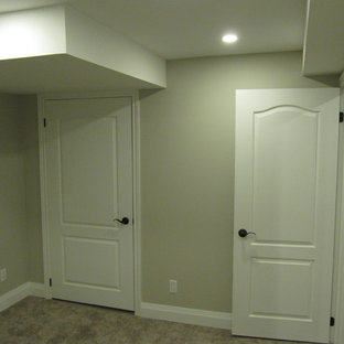 Ejemplo de sótano en el subsuelo moderno, pequeño, con paredes grises, moqueta, chimeneas suspendidas, marco de chimenea de piedra y suelo gris