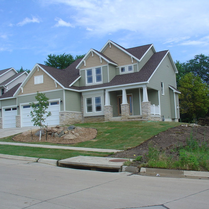 Example of a mid-sized arts and crafts green two-story vinyl exterior home design in Cedar Rapids with a clipped gable roof