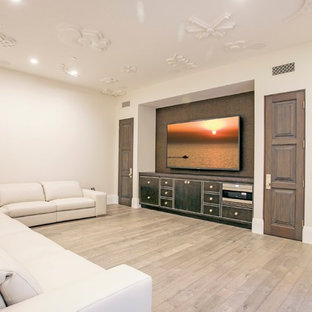 Réalisation d'une salle de cinéma tradition ouverte et de taille moyenne avec un téléviseur fixé au mur, un mur blanc et un sol en bois clair.