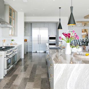 Large l-shaped kitchen pantry in Orange County with a drop-in sink, flat-panel cabinets, grey cabinets, marble benchtops, white splashback, glass tile splashback, stainless steel appliances, limestone floors and with island.