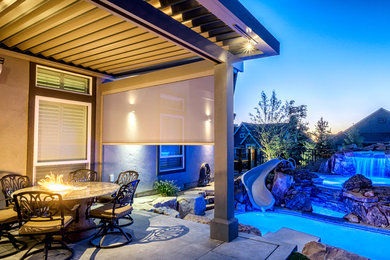 Example of a large minimalist backyard concrete patio design in Boise with a fire pit and an awning